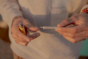 person holding cigarette stick with lighter